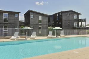 a pool with chairs and umbrellas in front of buildings at Vacancéole - Domaine de Saint Orens in Montréal