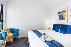 Un dormitorio con una cama y una silla azul. en The Cornerstone on Inkerman, en Melbourne