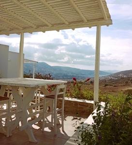 een witte tafel en stoelen op een patio met uitzicht bij La Casa dei Gatti Paros in Kalami