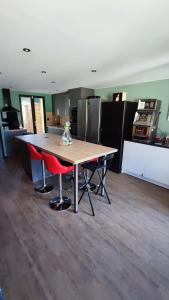 a kitchen with a wooden table and two red chairs at Deauville Bonny and clyde room in Valsemé