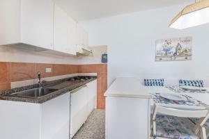 a kitchen with white cabinets and a sink at Capo Ai Pini - Bilo Elisa in Lacona +6 photos