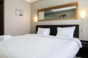 a bedroom with a large white bed with a large mirror at Minimalist Studio The Oasis Apartment near Omni Hospital Cikarang By Travelio in Cikarang
