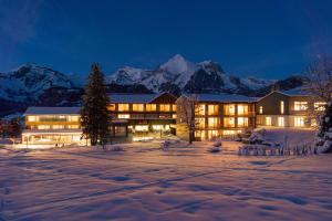 a building in the snow at night with mountains at Hotel Stump's Alpenrose in Wildhaus