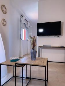 a living room with a table and a tv on a wall at Hispalis Mazagón Beach 303 in Mazagón