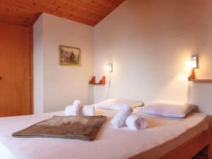 een slaapkamer met een bed met witte lakens en kussens bij Chalet Les Etoiles by Interhome in Nendaz