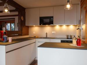 een keuken met witte kasten en zwarte aanrechtbladen bij Chalet Les Etoiles by Interhome in Nendaz