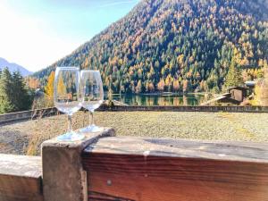 dois copos de vinho sentados numa saliência com vista para um lago em Apartment Parc C013 by Interhome em Champex