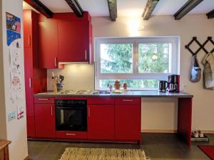 a kitchen with red cabinets and a sink and a window at Holiday Home Chalet Ninette by Interhome in Eischoll +19 photos