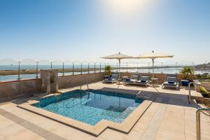 a swimming pool on a patio with chairs and umbrellas at Hotel Quinta do Lago in Quinta do Lago