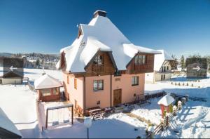 a house with snow on top of it in the snow at Vila Zlatna Pahulja in Bajina Bašta