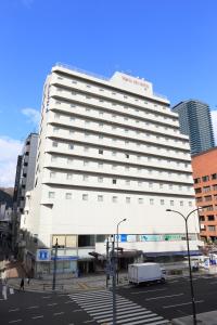 a large white hotel building in a city at Kobe Sannomiya Tokyu REI Hotel in Kobe