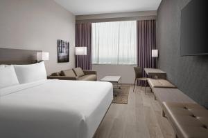 a hotel room with a white bed and a couch at AC Hotel by Marriott Orlando Downtown in Orlando