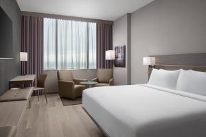 a hotel room with a large white bed and a chair at AC Hotel by Marriott Orlando Downtown in Orlando