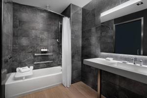 a bathroom with a tub and a sink and a mirror at AC Hotel by Marriott Orlando Downtown in Orlando