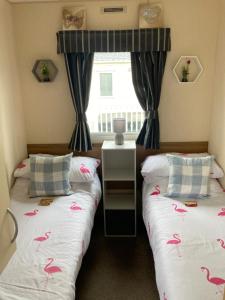 2 Betten in einem Zimmer mit rosa Vögeln auf der Bettwäsche in der Unterkunft Tattershall Lakes Pet Friendly Hot Tub Breaks in Tattershall + 12 Fotos