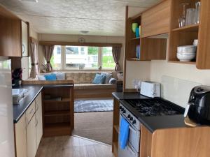 eine Küche mit einem Herd und einer Couch in einem Wohnwagen in der Unterkunft Tattershall Lakes Pet Friendly Hot Tub Breaks in Tattershall