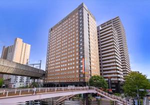un edificio alto con un puente en una ciudad en APA Hotel Sendai Eki Itsutsubashi, en Sendai