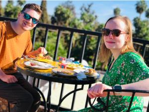 a man and a woman sitting at a table with food at Riad Jennah Rouge in Marrakesh