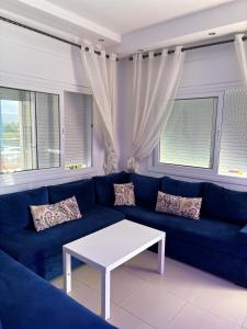 a blue couch with a white coffee table in a living room at Superbe appartement au centre de Cabo Negro en résidence avec piscines et tobogan in Cabo Negro