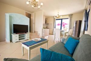 ein Wohnzimmer mit einer Couch, einem Fernseher und einem Tisch in der Unterkunft Villa Panoramica 5 in Torre Pali 