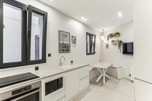 een witte keuken met een wastafel en een tafel bij Maison atypique de 82 m2 sur 4 niveaux proche Saint Mande in Vincennes