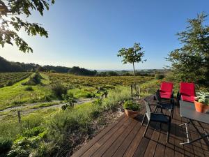 two chairs and a table on a wooden deck looking at a field at Le Ponant in Vaison-la-Romaine