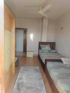 a bedroom with two beds and a ceiling fan at Nubian Mood in Naj‘ al Maḩaţţah