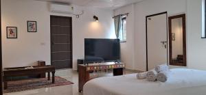 Un dormitorio con una cama y un televisor de pantalla plana. en Jangala Baga Beach - French welcome, tropical garden, close to the beach, en Arpora