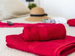 a pile of red towels on a bed with a hat at 1A Apartment Abrigos, Wifi and balcony in Los Abrigos