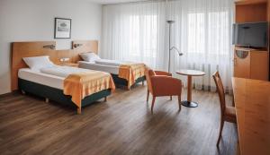 a hotel room with two beds and a table at Ariva Boardinghouse Platanenhof in Mannheim