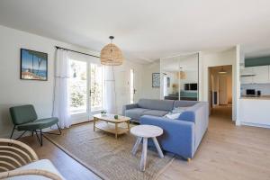 ein Wohnzimmer mit einem blauen Sofa und einem Tisch in der Unterkunft Villa Eglantine à deux pas de la plage PYLA SUR MER in La Teste-de-Buch