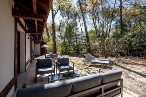 eine Terrasse mit einem Sofa, 2 Stühlen und einem Tisch in der Unterkunft Villa Eglantine à deux pas de la plage PYLA SUR MER in La Teste-de-Buch