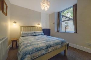 Un dormitorio con una cama y una ventana y una lámpara de araña. en 2 Bed Ground Floor Beach Location, en Aberdyfi