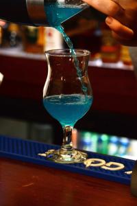 a person pours a blue drink into a glass at Fiori Hotel in Erbil