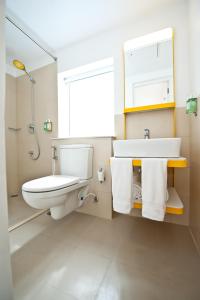 a bathroom with a toilet and a sink and a mirror at bloomrooms @ Indiranagar in Bangalore