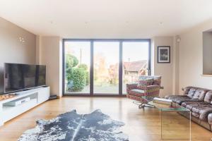 a living room with a couch and a flat screen tv at Woodside Lodge, surrounded by woodland and beautiful gardens in Wrington