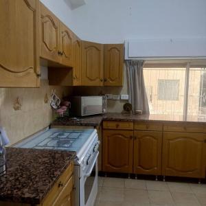een keuken met houten kasten en een kookplaat met oven bij B Beitna in Amman