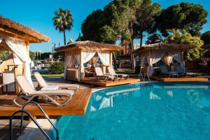 a swimming pool with chairs and gazebos at Ducale Lara - Ultra All Inclusive in Lara