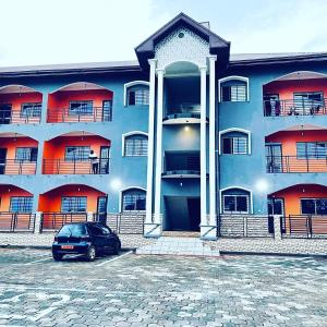 a blue building with a car parked in front of it at Appartement Ella Meublé in Yaoundé