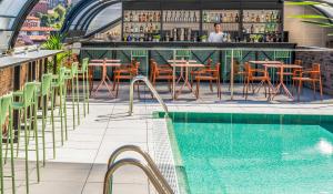 a bar with tables and chairs next to a swimming pool at Axel Hotel Bilbao - Adults Only in Bilbao