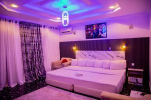 una camera da letto con un grande letto bianco con illuminazione viola di Skyrock Hotels Ikeja a Ikeja