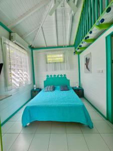 a bedroom with a blue bed and two windows at Alpinia bungalow in Sainte-Anne