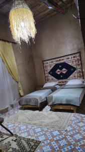 a bedroom with two beds and a chandelier at berber desert home for rent in Merzouga