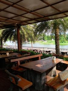 a group of wooden tables and chairs under a pavilion at Evergreen Resort Chanthaburi in Chanthaburi