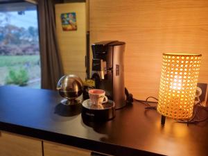 a coffee maker and a lamp on a counter at La cabane 27 ~ Chalet cosy au bord du lac de Peyre in Labouheyre