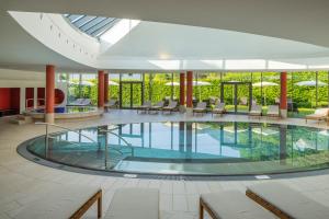 una grande piscina in un edificio con sedie e tavoli di Villa Seilern Vital Resort a Bad Ischl