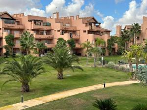 a large building with palm trees in front of it at Mar Menor Golf Resort 2 Bed Apartment in Los Martínez