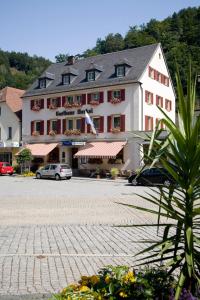 un grand bâtiment avec des voitures garées devant lui dans l'établissement Gasthaus Merkel Hotel, à Bad Berneck im Fichtelgebirge