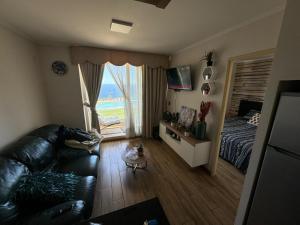 sala de estar con sofá, cama y ventana en Departamento con vista al mar, en Viña del Mar