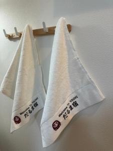 drei Handtücher mit Schreiben auf einem Kleiderständer in der Unterkunft 青砥駅徒步5分 Aoto だるま宿 in Tokio + 23 Fotos
